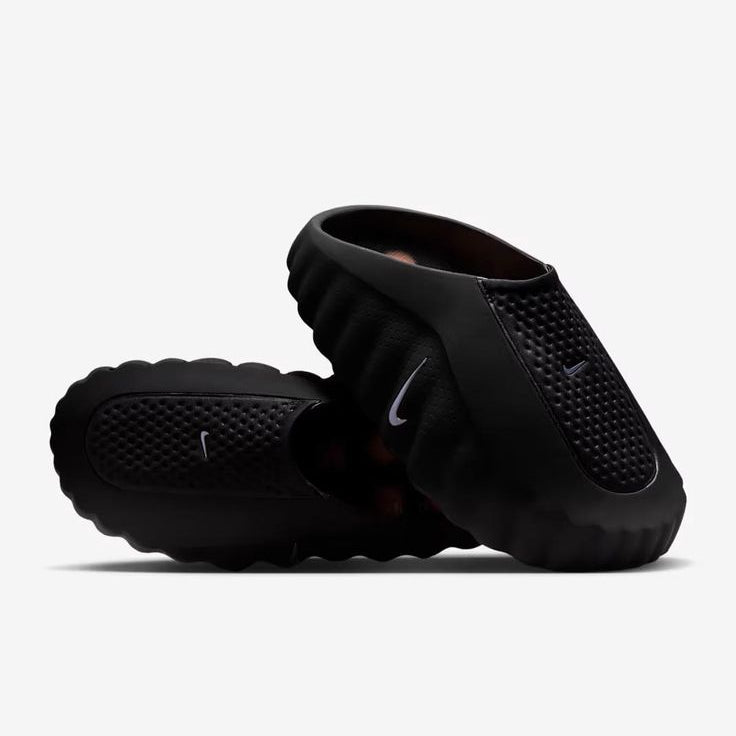 Black Nike slides on a white background